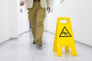 Picture of Man Walking Down Hallway With Wet Floor Sign