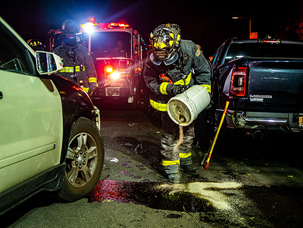 firefighter putting sand on the road after a car accident