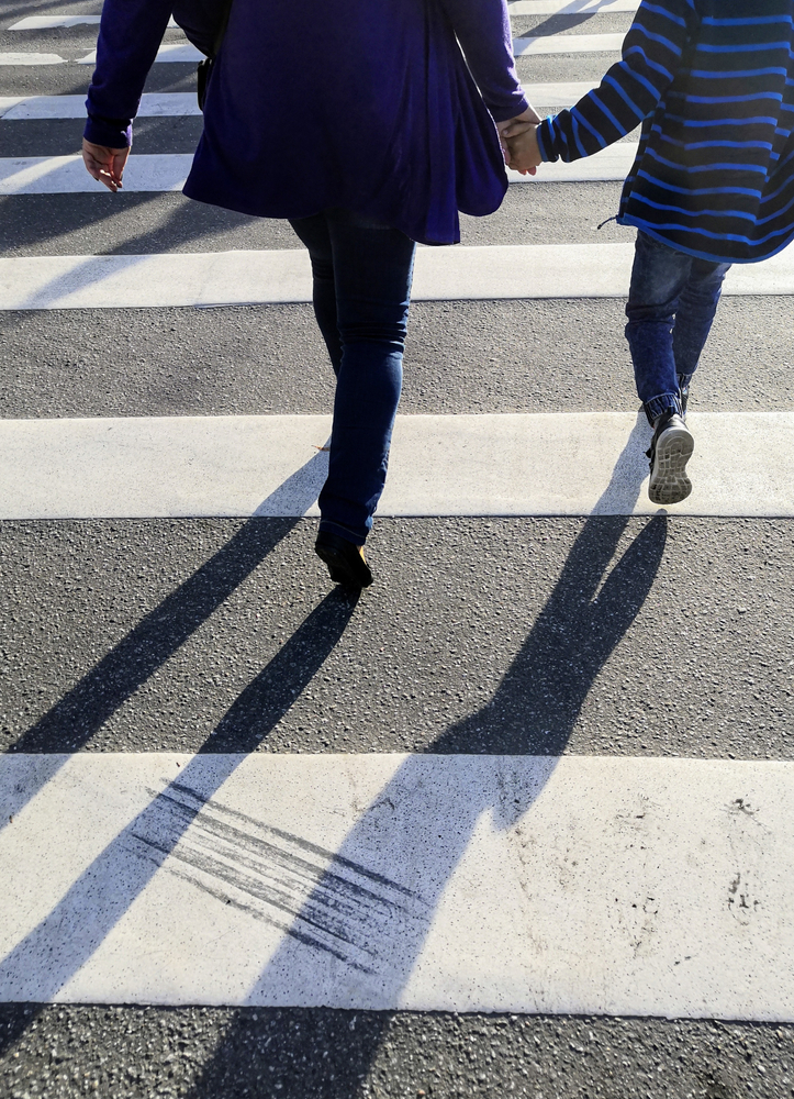 parent and child holding hands crossing pedestrian crosswalk
