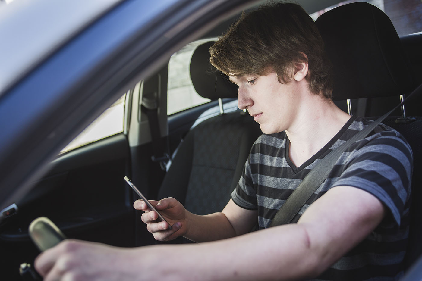 teen driver looking at his phone - teen driving accident