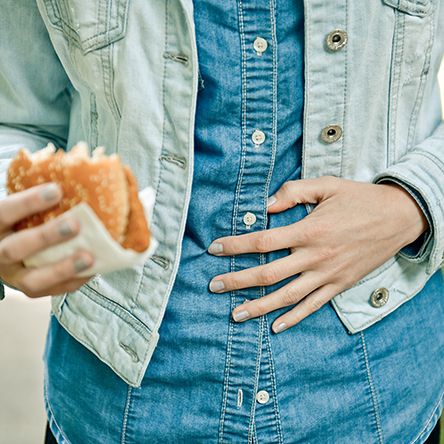 woman holding stomach after eating burger