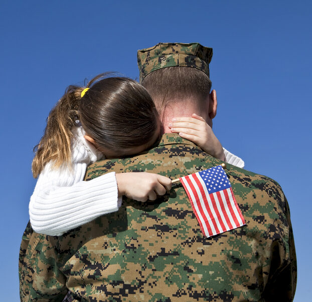 Child holding American flag in military father's arms