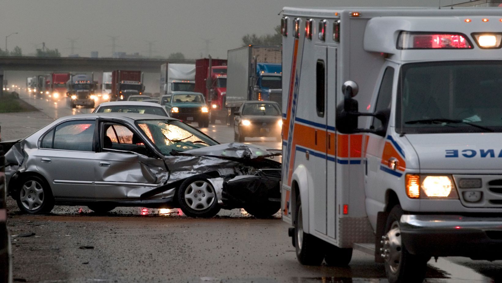 A severely damaged sedan is shown crashed on a busy highway in Bethesda, Maryland, highlighting a rideshare Uber accident scene. The image includes a nearby ambulance and heavy traffic flow, indicating emergency response. Regan Zambri Long PLLC, reachable at (202) 972-3767, provides legal support for Uber passengers and drivers injured in Bethesda traffic collisions. This realistic image underscores the chaotic aftermath of a rideshare incident, intended to reflect the importance of contacting an experienced Uber accident attorney immediately.