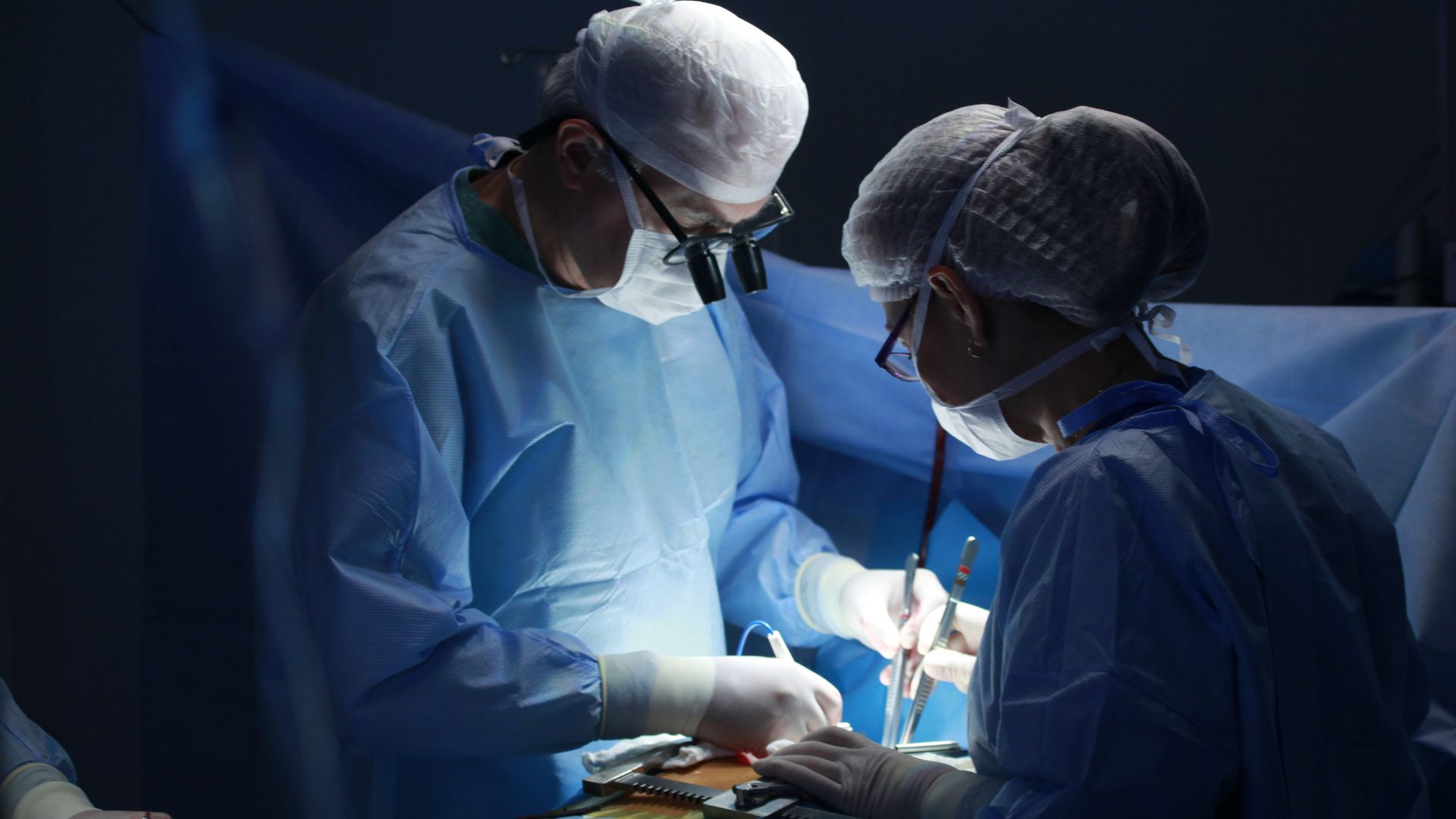 This image captures an intense surgical scene with two masked surgeons performing a procedure under bright, focused lighting. Surrounded by sterile blue drapes and surgical tools, the professionals are deeply engaged in an operation—highlighting the high-stakes environment where medical errors can occur. Such situations form the basis for malpractice lawsuits handled by a College Park, Maryland medical malpractice lawyer. When surgical negligence, anesthesia mistakes, or procedural complications cause harm, victims and families turn to experienced legal counsel like Regan Zambri Long PLLC. Contact a College Park malpractice attorney today at (202) 937-3310 for dedicated support.
