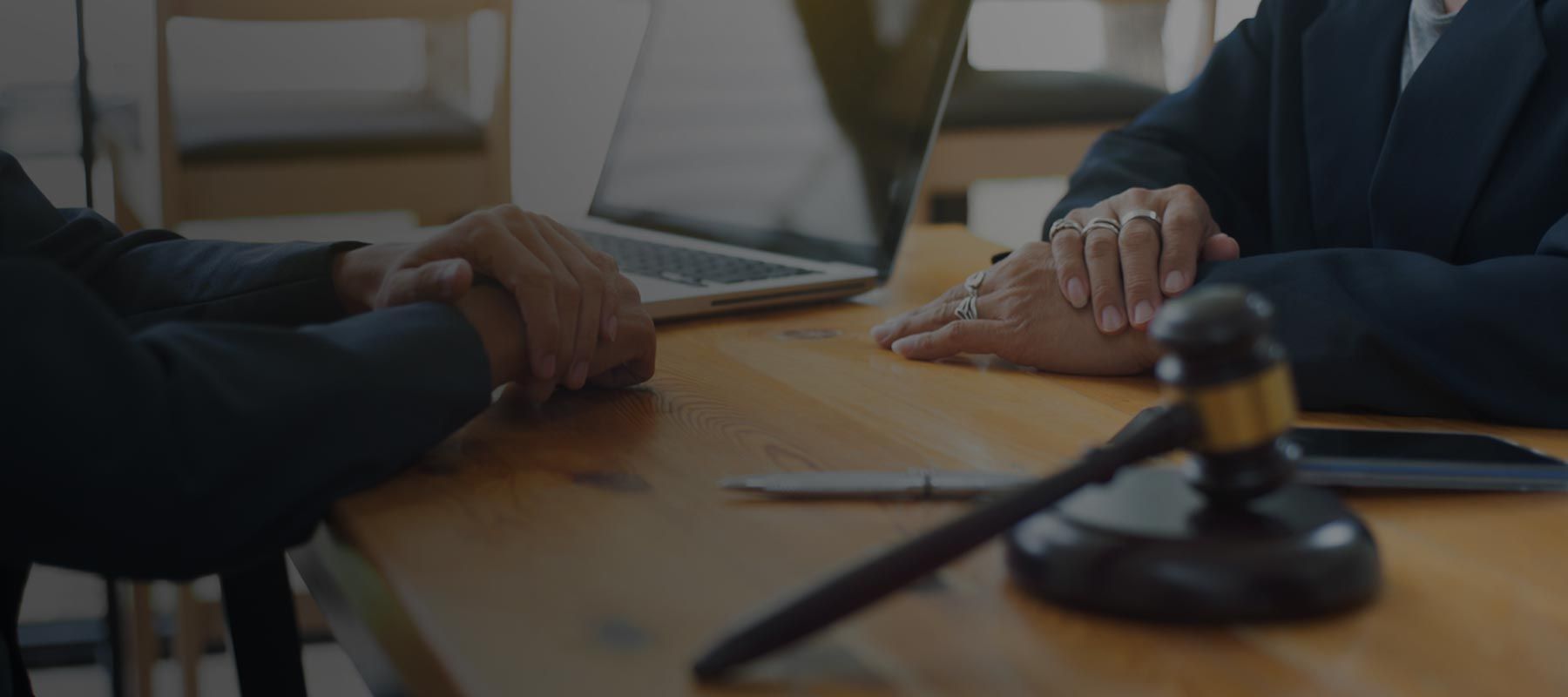 Close-up image showing a legal consultation between a client and attorney, discussing whether Maryland is a no-fault state for auto accidents. Hands rest on a wooden desk near a gavel and open laptop, reflecting the seriousness of navigating personal injury laws. Maryland follows a traditional fault-based system, meaning the at-fault driver is financially responsible for damages, unlike no-fault states. Regan Zambri Long PLLC offers detailed advice and representation for Maryland residents dealing with accident claims. Call +1 (202) 937-3310 to understand your legal options.